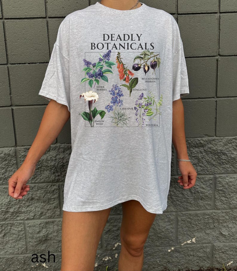 May include: Ash gray t-shirt with the text "DEADLY BOTANICALS" above a botanical illustration. The illustration features drawings of various plants, including Elderberries, Foxglove, and Wisteria. The shirt is a relaxed fit.
