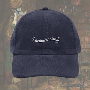 May include: Navy blue corduroy baseball cap with a curved brim. The cap features the white text "to define is to limit" embroidered on the front. The hat has a structured crown and an adjustable strap.