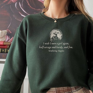 May include: A dark green sweatshirt with a white graphic print of a woman in a circle with the text "I wish I were a girl again, half-savage and hardy, and free. -Wuthering Heights".