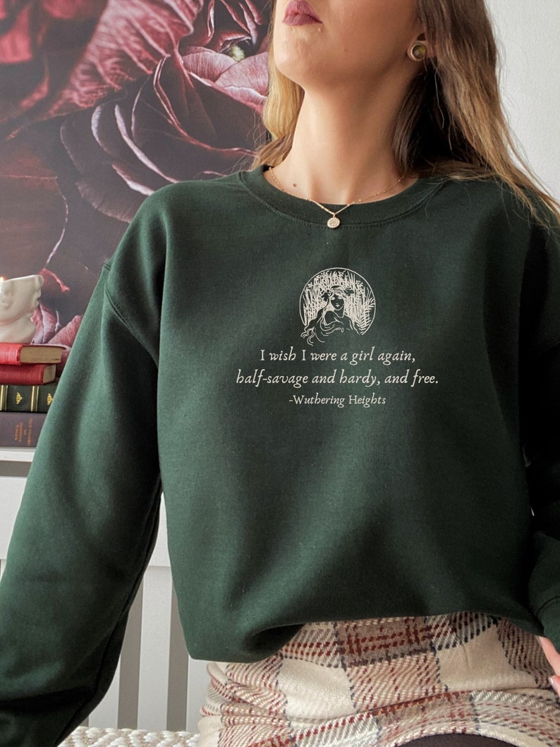 May include: A dark green sweatshirt with a white graphic print of a woman in a circle with the text "I wish I were a girl again, half-savage and hardy, and free. -Wuthering Heights".