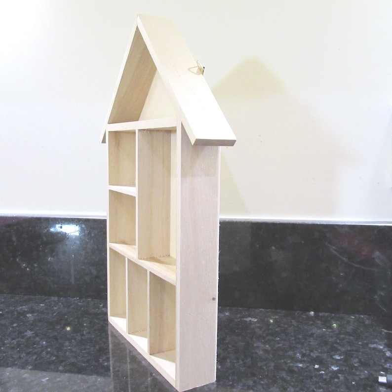 Wooden House Shaped Display Shelves Unit Suitable to display Small Ornaments, Dolls House Miniatures, Thimbles, Lego Figures The unit measures 30cm High x 22cm Wide x 4.5cm Deep Can be Free-Standing or Wall Mounted. Supplied with two hanging hooks.