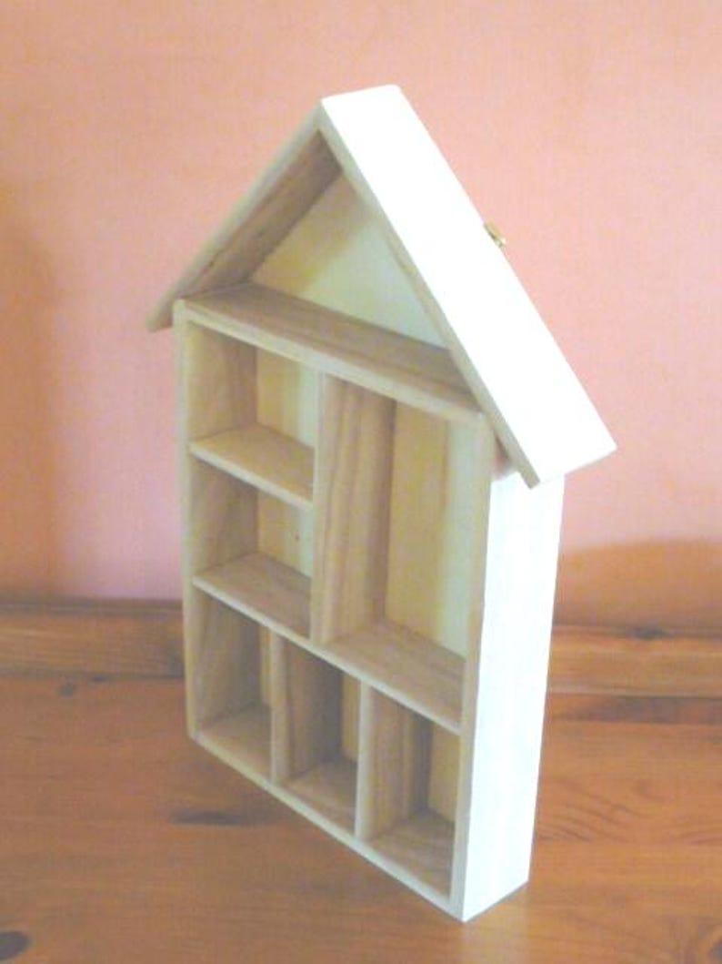 Wooden House Shaped Display Shelves Unit Suitable to display Small Ornaments, Dolls House Miniatures, Thimbles, Lego Figures The unit measures 30cm High x 22cm Wide x 4.5cm Deep Can be Free-Standing or Wall Mounted. Supplied with two hanging hooks.