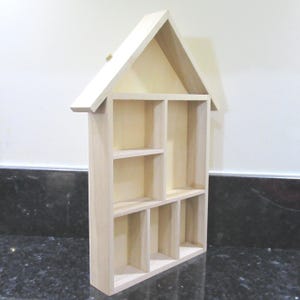 Wooden House Shaped Display Shelves Unit Suitable to display Small Ornaments, Dolls House Miniatures, Thimbles, Lego Figures The unit measures 30cm High x 22cm Wide x 4.5cm Deep Can be Free-Standing or Wall Mounted. Supplied with two hanging hooks.