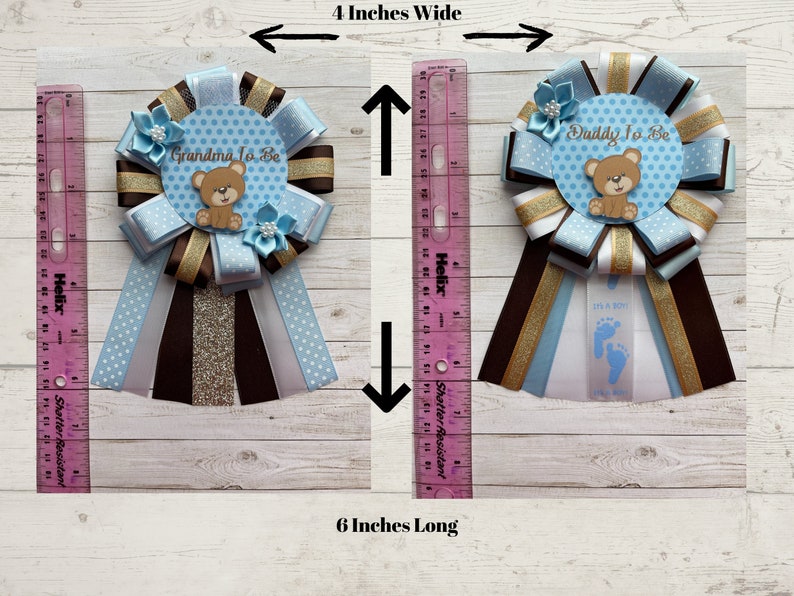 May include: Two blue and brown baby shower sashes with a teddy bear design. The sashes are 4 inches wide and 6 inches long. One sash says "Grandma To Be" and the other says "Daddy To Be".