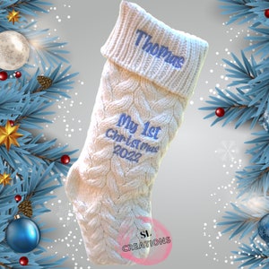 May include: White knitted Christmas stocking with blue embroidery that reads "Thomas", "My 1st Christmas 2022", and "SL Creations".
