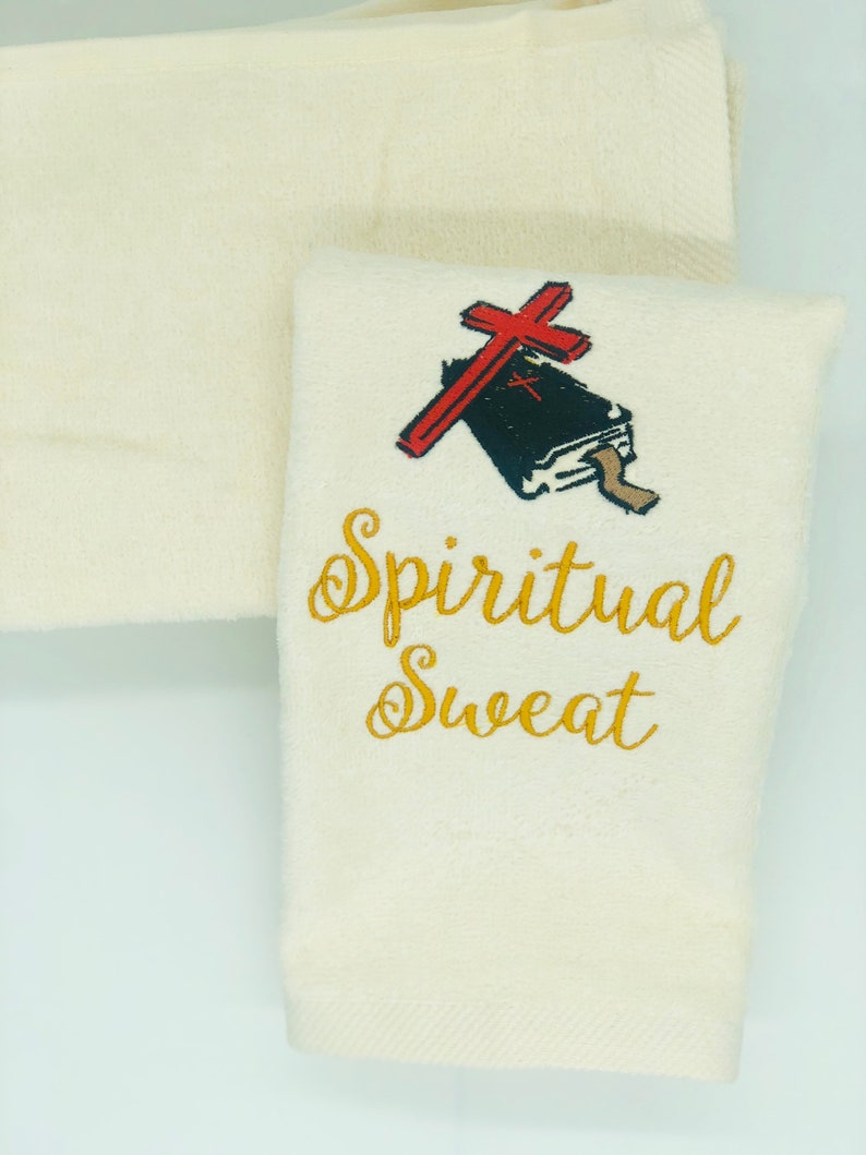 May include: White cotton hand towel with gold embroidery that reads "Spiritual Sweat" and a red cross over a black book.