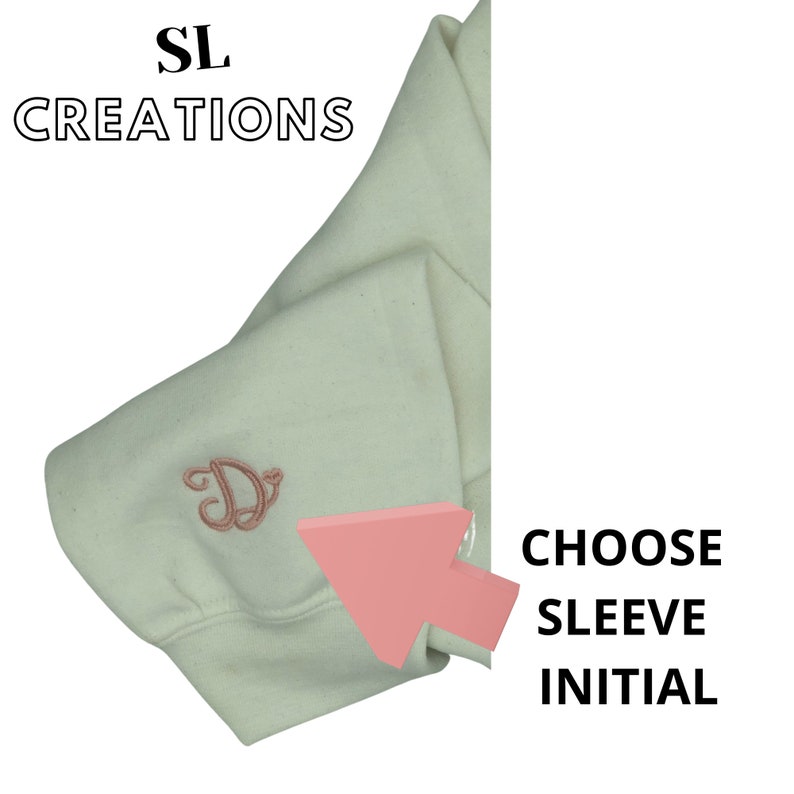 Puede incluir: Una sudadera blanca con una letra "D" bordada en rosa en la manga. El texto "CHOOSE SLEEVE INITIAL" es visible en el lado derecho de la imagen.