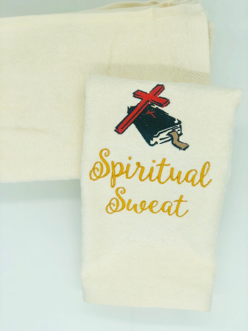 May include: White hand towel with gold embroidery that reads "Spiritual Sweat". A red cross with a black bible is embroidered above the text.