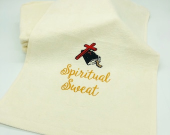 May include: White cotton towel with gold embroidery that reads "Spiritual Sweat". A red cross is embroidered above the text.