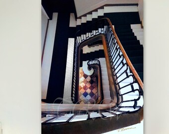 May include: A black and white photograph of a spiral staircase with a black railing. The staircase is made of wood and has a chequered tile floor.