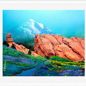 May include: A colourful landscape painting depicting a mountain range with snow-capped peaks, red rock formations, and a winding path through a field of purple wildflowers. The painting is signed "T. Rowan 2020" in the bottom left corner.