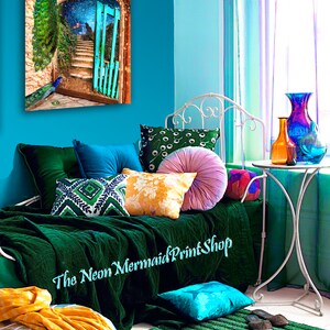 May include: A colourful interior with a peacock art print, emerald green bedding, and assorted cushions. A silver ottoman with a yellow throw and a green rug contribute to the room's eclectic style. The text "The Neon Mermaid Print Shop" is visible.