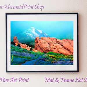 May include: A fine art print depicting a scenic landscape with a mountain range featuring snow-capped peaks, red rock formations, and a path leading through a field of wildflowers. The print is titled "The Neon Mermaid Print Shop" and is signed "Caden Rowan 2020".