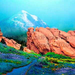 May include: A scenic landscape with a mountain in the background, red rock formations in the foreground, and a path leading through a field of purple wildflowers.