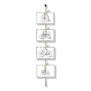 Può includere: Un'applique da parete con quattro stampe rettangolari di illustrazioni di biciclette vintage in bianco e nero. Le stampe sono tenute da mollette di legno su uno spago naturale, con un pomello nero in alto e un peso di metallo in basso.