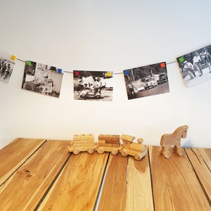 May include: A wooden toy train with three cars and a wooden horse on a wooden table. The train is made of natural wood and has a simple design. The horse is also made of natural wood and has a simple design.