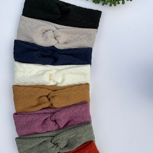 Puede incluir: Una pila de ocho diademas anudadas en varios colores, incluyendo negro, beige, azul marino, blanco, marr&oacute;n, morado, verde y rojo. Las diademas est&aacute;n hechas de una tela suave y texturizada.