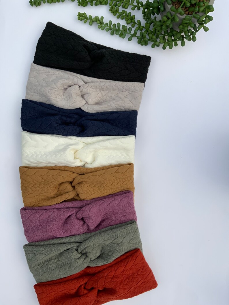 Puede incluir: Un conjunto de ocho diademas anudadas en varios colores, incluyendo negro, beige, azul marino, blanco, marr&oacute;n, morado, verde y rojo. Las diademas est&aacute;n hechas de una tela suave y texturizada.