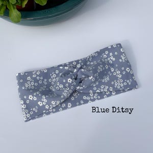Pu&ograve; includere: Una fascia blu con un motivo floreale bianco. Il tessuto &egrave; annodato nella parte superiore. Il testo "Blue Ditsy" &egrave; stampato in basso a destra nell'immagine. Questo accessorio &egrave; adatto a vari tipi di acconciatura.
