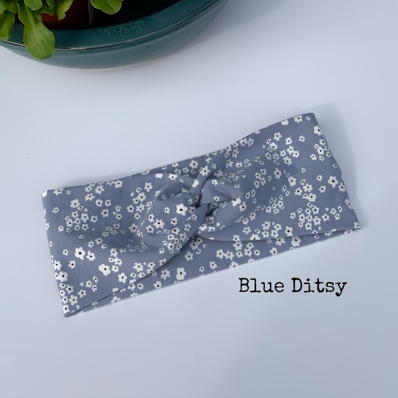 Pu&ograve; includere: Una fascia blu con un motivo floreale bianco. Il tessuto &egrave; annodato nella parte superiore. Il testo "Blue Ditsy" &egrave; stampato in basso a destra nell'immagine. Questo accessorio &egrave; adatto a vari tipi di acconciatura.