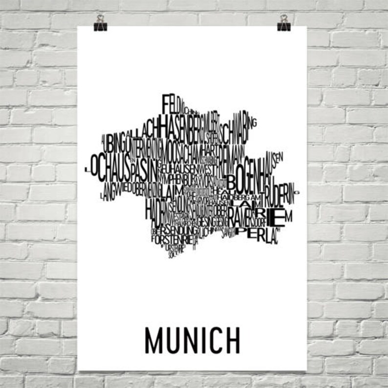 May include: A black and white typography art print of the city of Munich, Germany. The print features the names of the city's districts and neighborhoods arranged in a shape resembling the city's outline. The word "Munich" is printed in large letters at the bottom of the print.