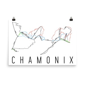 May include: A white poster featuring a black and coloured line drawing of a mountain ski map. The word "CHAMONIX" is printed in large, black, sans-serif letters at the bottom. Two black binder clips hold the poster in place.