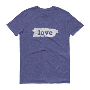 Puede incluir: Camiseta azul con la palabra "love" impresa en blanco sobre una forma rectangular gris claro. La camiseta tiene mangas cortas y cuello redondo.