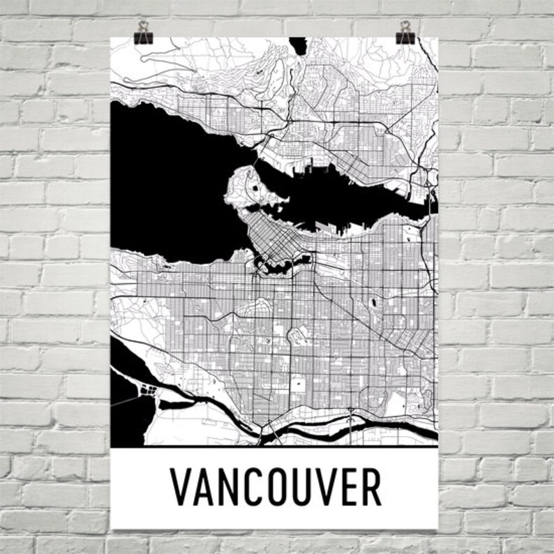 May include: A black and white map of Vancouver, Canada, displayed on a white poster. The map details the city's streets, waterways, and surrounding areas. The word "VANCOUVER" is printed in bold, black letters at the bottom of the poster.