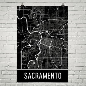 May include: Black and white map of Sacramento, California. The map shows the city's streets and waterways. The word "Sacramento" is printed in white at the bottom of the map.