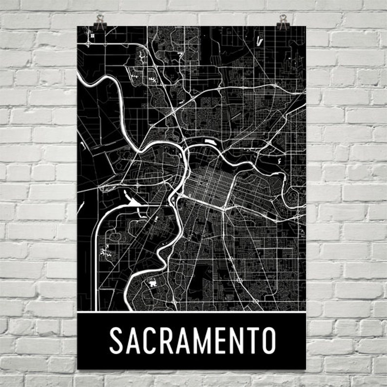May include: Black and white map of Sacramento, California. The map shows the city's streets and waterways. The word "Sacramento" is printed in white at the bottom of the map.