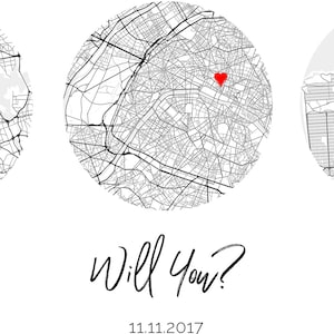 May include: A circular black and white street map print featuring a red heart icon placed over a specific location. Below the map, the text reads Will You? followed by the date 11.11.2017 in a simple black font on a plain white background.