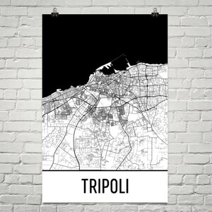 May include: A black and white map of Tripoli, Libya, with a black upper section and a white lower section with the city name in bold, sans-serif font. The map details the city's road network and coastal features.