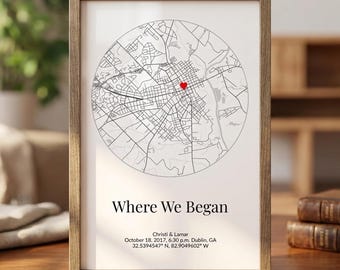 Może przedstawiać: Oprawiony wydruk z okrągłą mapą i czerwonym znacznikiem. Tekst "Where We Began" znajduje się pod mapą, wraz z imionami, datą, godziną i współrzędnymi. Rama jest w kolorze jasnobrązowym.