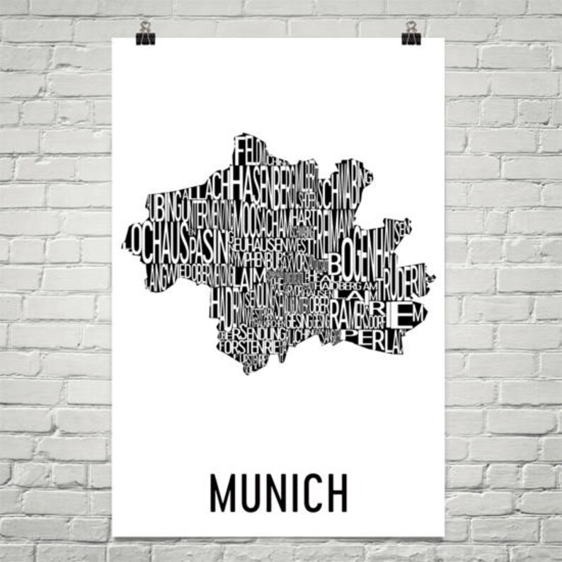 May include: Black and white typography art print of the city of Munich, Germany. The print features the city's name in large letters at the bottom and a map of the city made up of the names of its neighborhoods.