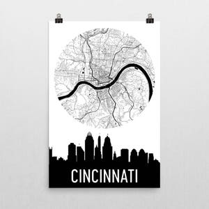 May include: A black and white print of Cincinnati, Ohio. The print features a circular map of the city, a black skyline silhouette, and the city's name in bold white letters. The map shows the city's streets and the Ohio River.