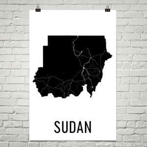 May include: A black and white map of Sudan with the country name "SUDAN" printed in white below the map.