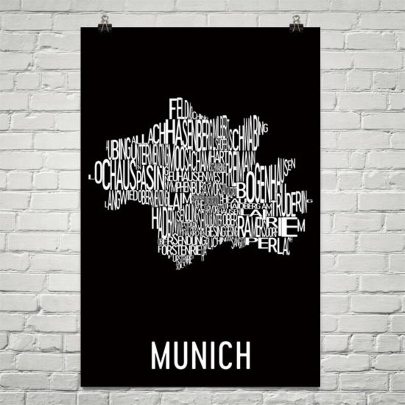 May include: A black and white typography art print of the city of Munich, Germany. The print features the names of the different districts of Munich arranged in the shape of the city's outline. The text "MUNICH" is printed in white at the bottom of the print.