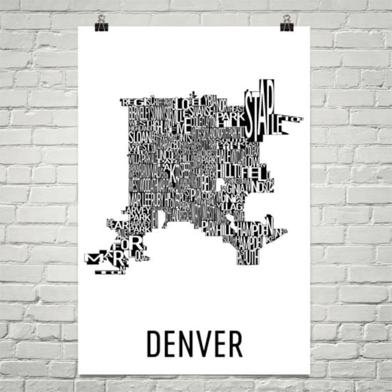 May include: A black and white poster featuring a map of Denver, Colorado, composed of neighborhood names. The word "DENVER" is printed in a bold, sans-serif font at the bottom of the poster. The poster is hanging on a white brick wall.