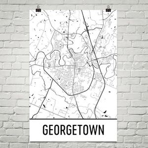 May include: A black and white map of Georgetown, Texas, printed on a white poster. The map shows the city's streets, waterways, and other geographical features. The word "GEORGETOWN" is printed in bold, black letters at the bottom of the poster.