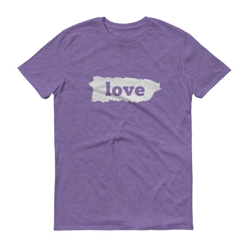 Puede incluir: Una camiseta morada con la palabra "love" impresa en blanco dentro de una forma rectangular blanca. La camiseta est&aacute; hecha de un material suave y tiene mangas cortas y cuello redondo.