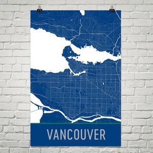 May include: A blue and white map of Vancouver, Canada, with a green stripe at the bottom. The city's name is printed in silver letters. The map is detailed, showing streets and waterways.