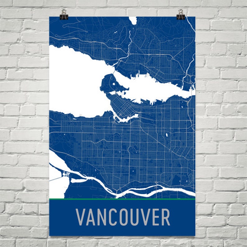 May include: A blue and white map of Vancouver, Canada, with a green stripe at the bottom. The city's name is printed in silver letters. The map is detailed, showing streets and waterways.