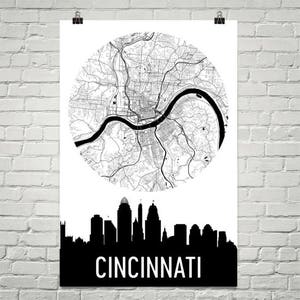 May include: A black and white poster featuring a detailed map of Cincinnati, Ohio, in a circular design. Below the map is a black silhouette of the city's skyline, with the city name in bold white letters.