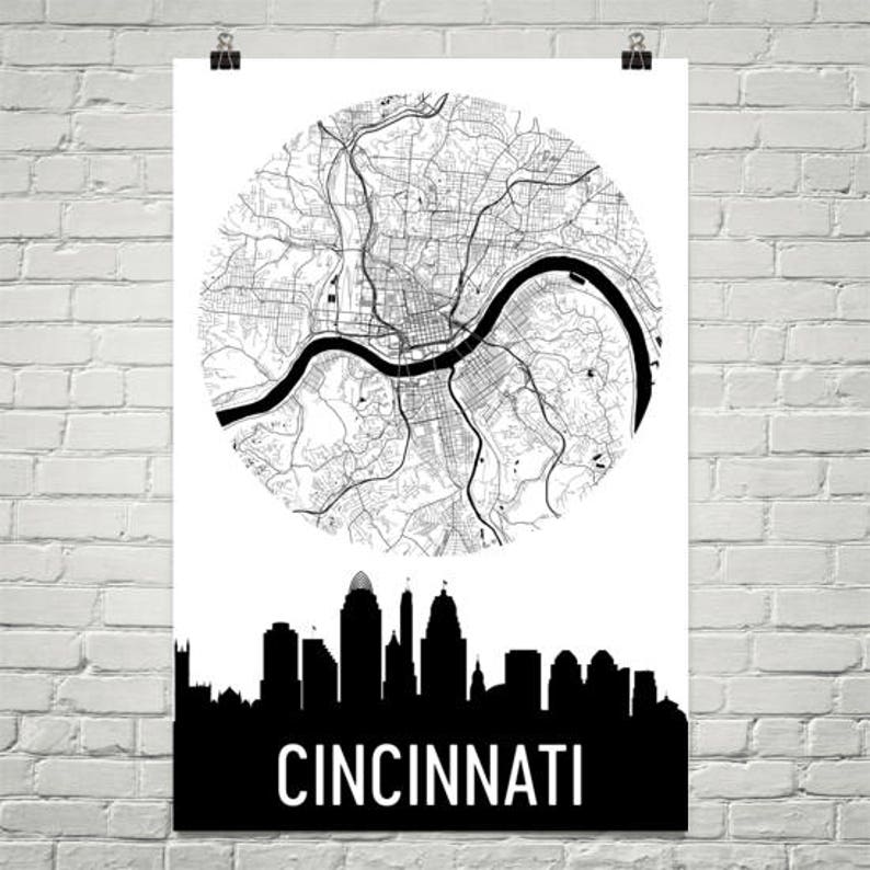 May include: A black and white poster featuring a detailed map of Cincinnati, Ohio, in a circular design. Below the map is a black silhouette of the city's skyline, with the city name in bold white letters.