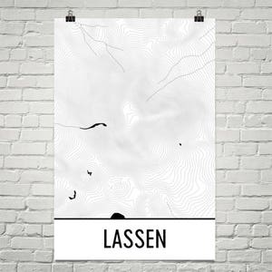 May include: A black and white topographic map print of Lassen, a mountain range in California. The print features detailed contour lines and is framed with a white border. The word "LASSEN" is printed in black at the bottom of the print.