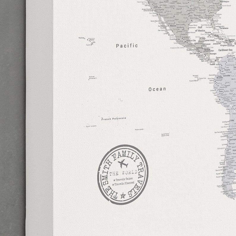 May include: A black and white world map print with the text "Pacific Ocean" and "French Polynesia." A circular stamp reads "The Smith Family Travels" with the words "Travels Taken" and "Travels Planned."