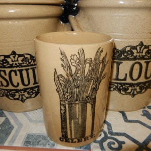 May include: Three ceramic jars with black and white designs. The jars are labelled "Biscuit", "Flour", and "Celery".