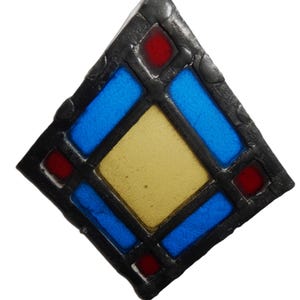 May include: A diamond-shaped stained glass suncatcher featuring a central yellow square pane surrounded by four rectangular blue panes and four small red square panes at the corners, all held together by a thick, textured black leaded frame.