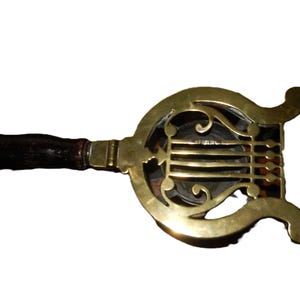 May include: An antique brass bed warmer with a dark wooden handle. The brass warmer has an ornate, openwork design with a circular shape and decorative curves. The handle is dark brown and appears to be made of wood.