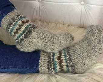 May include: A pair of grey wool socks with brown, white and blue stripes. The socks are knitted and have a fluffy texture.